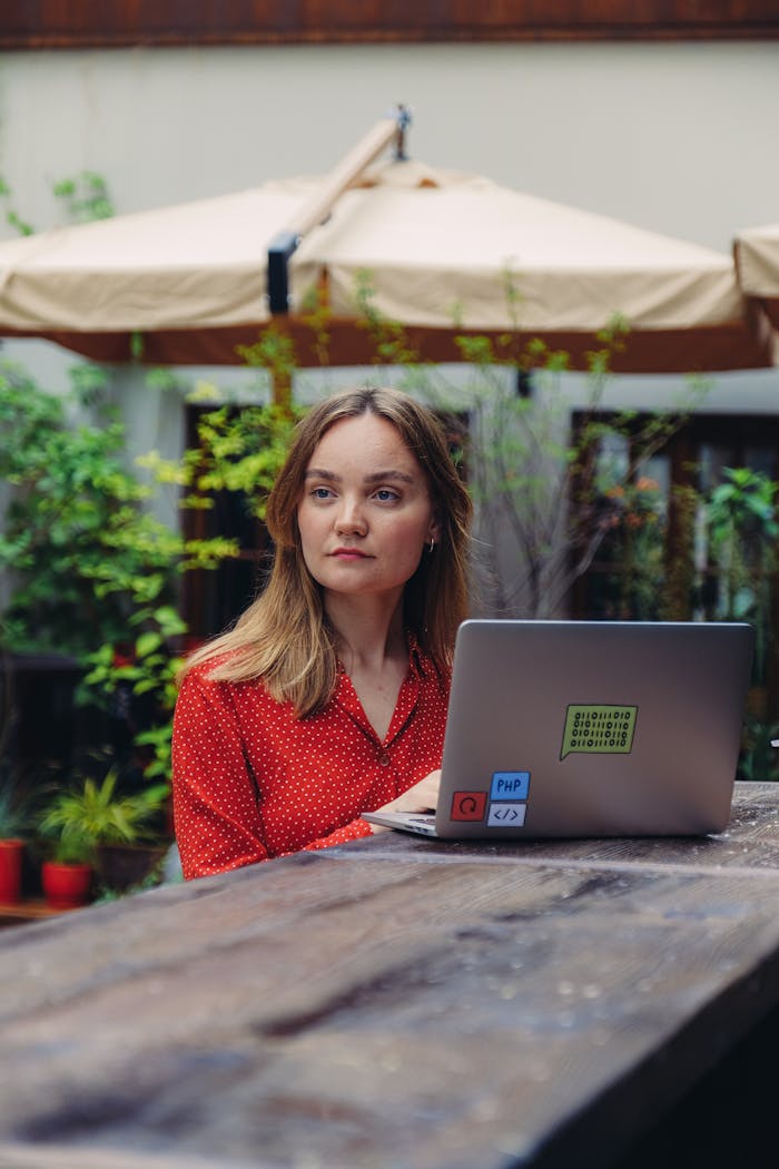 Woman in Red and Black Polka Dot Long Sleeve Shirt Using Macbook